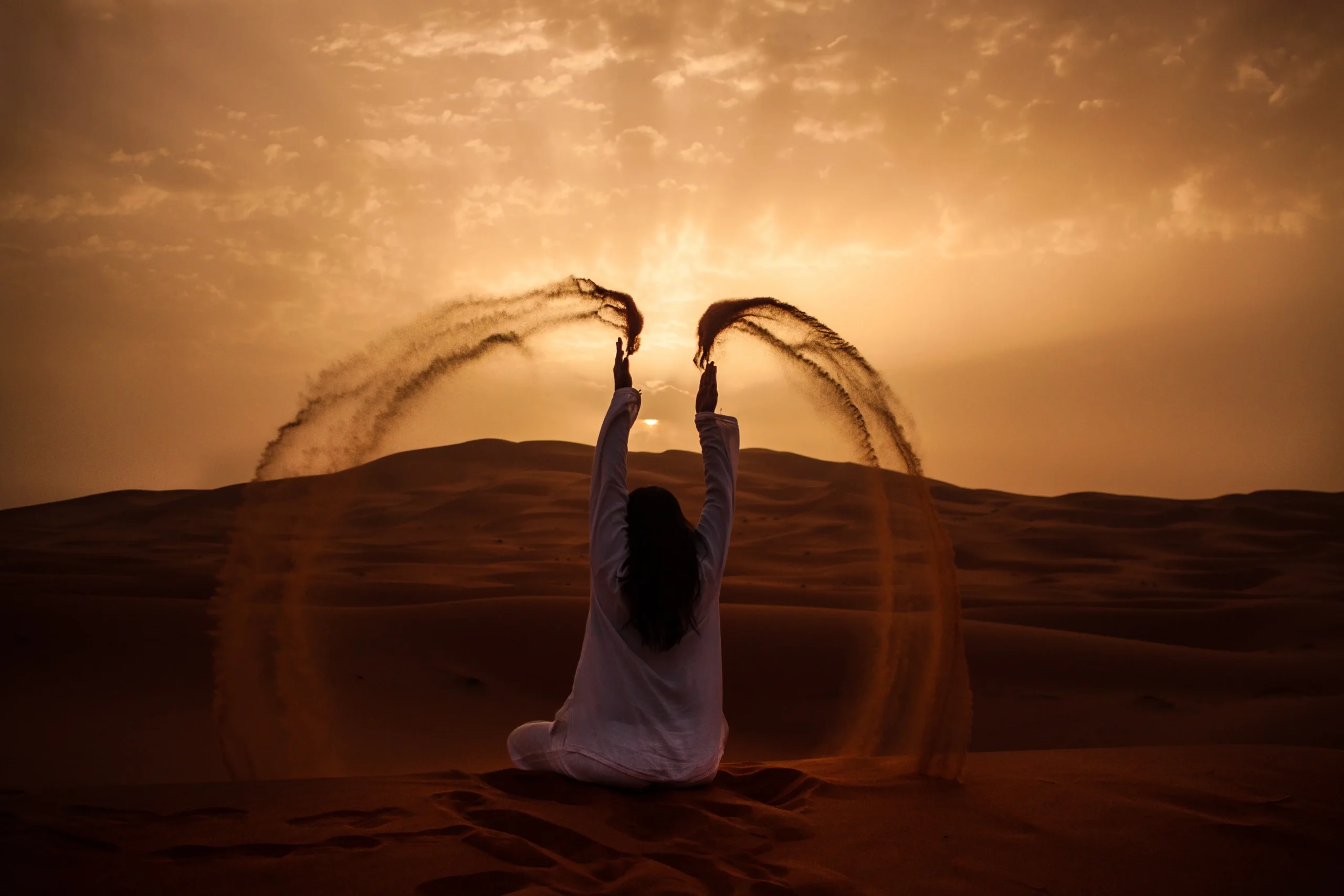 3 days Marrakech desert tour to Merzouga woman throwing sand on Sahara dunes at golden sunset